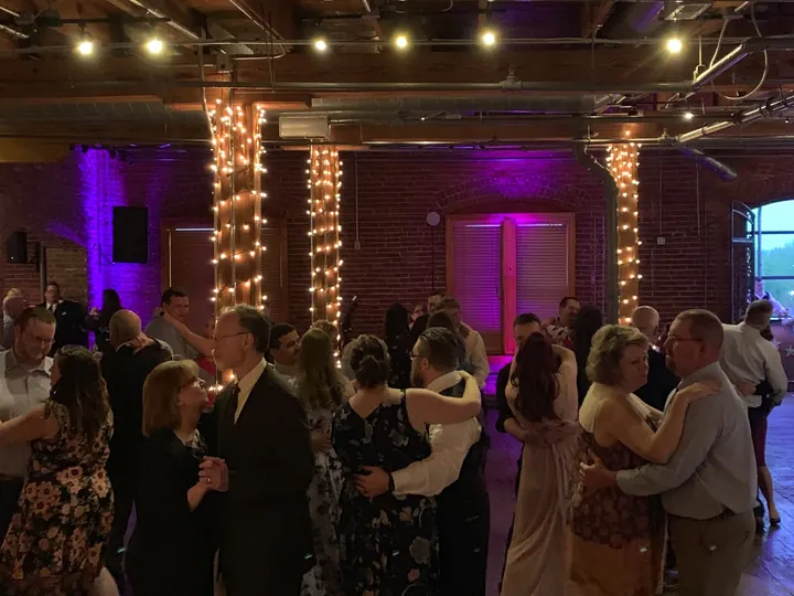 Couples dancing at a brick wedding venue with string lights