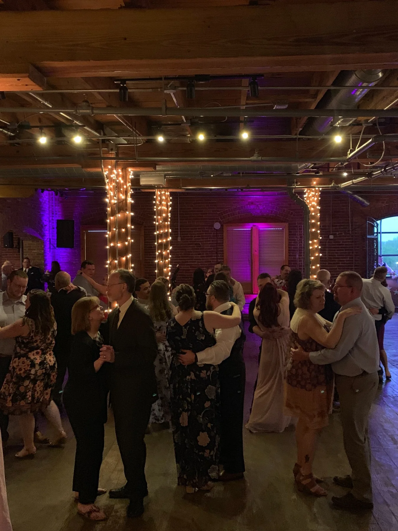 Couples slow dancing at a wedding reception in a brick venue