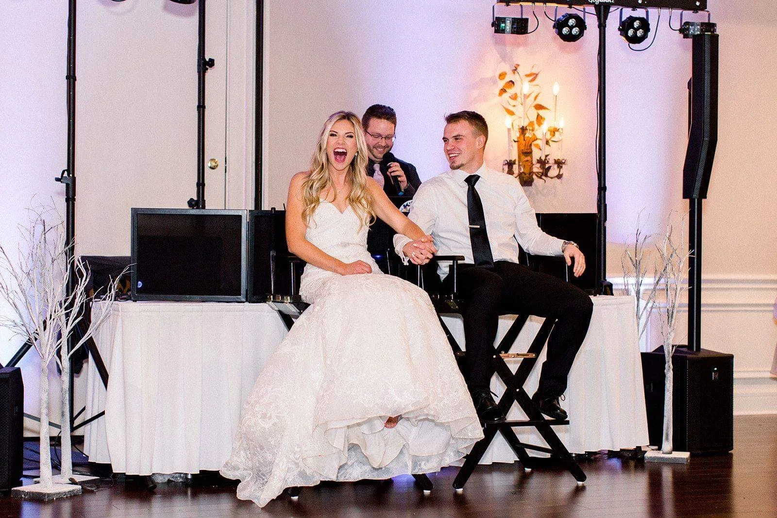 Bride and groom smiling together in front of a wedding DJ booth