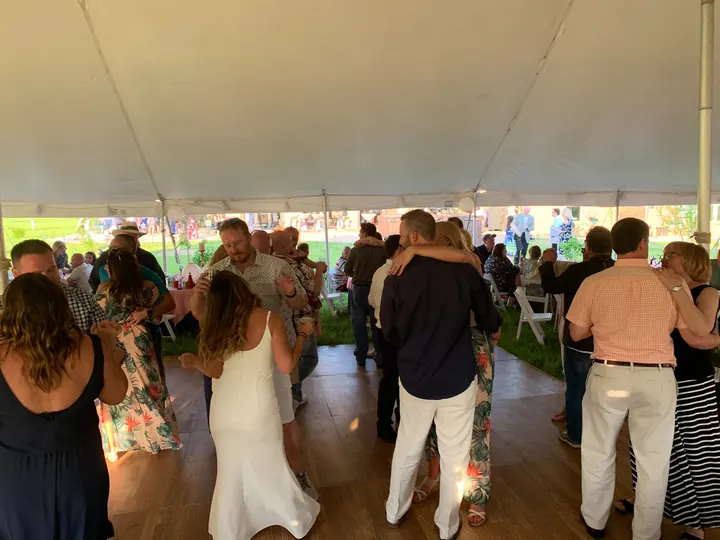 Wedding guests dancing beneath a reception tent
